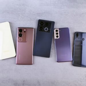 Flat lay of five modern smartphones on a gray surface, showcasing various designs.